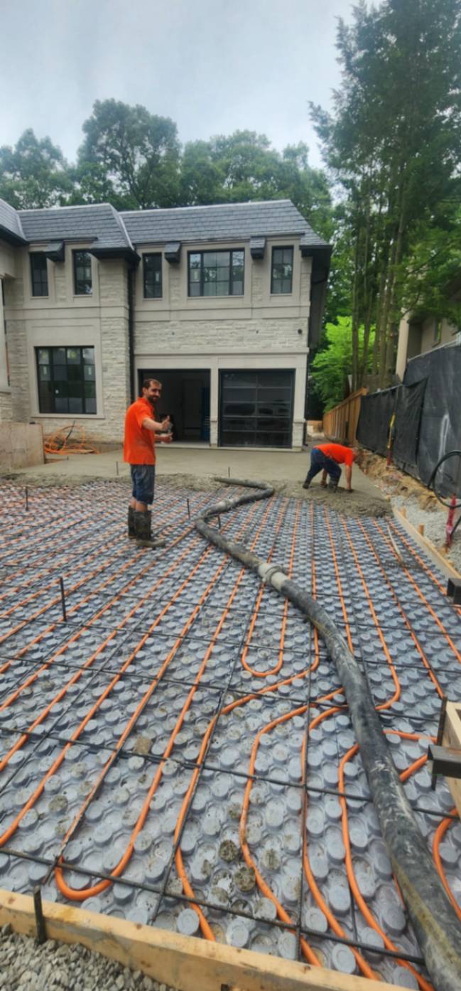 Concrete pump delivering concrete on a heated driveway in Toronto.