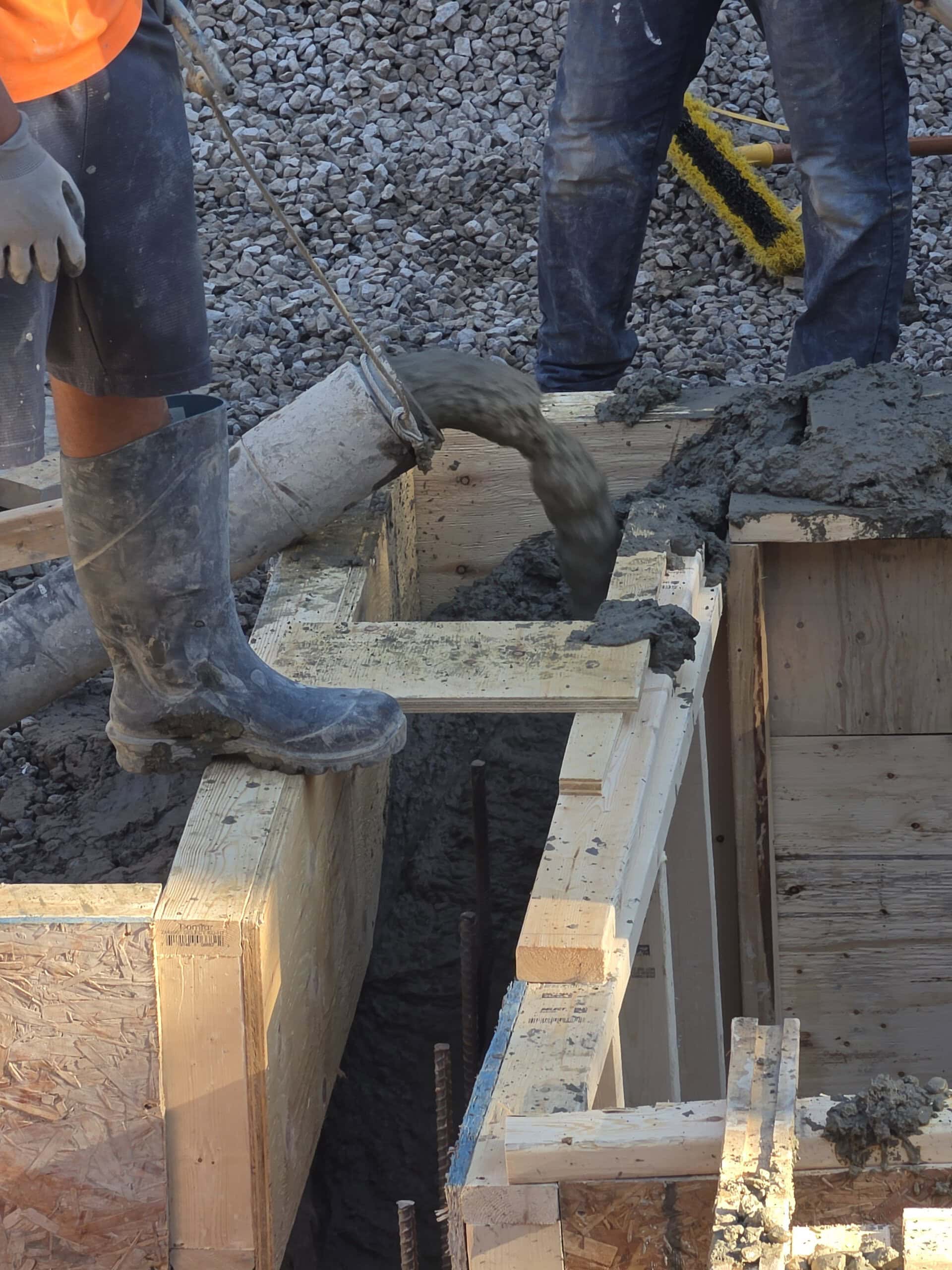 Concrete being pumped into footing formwork using a line pump hose.