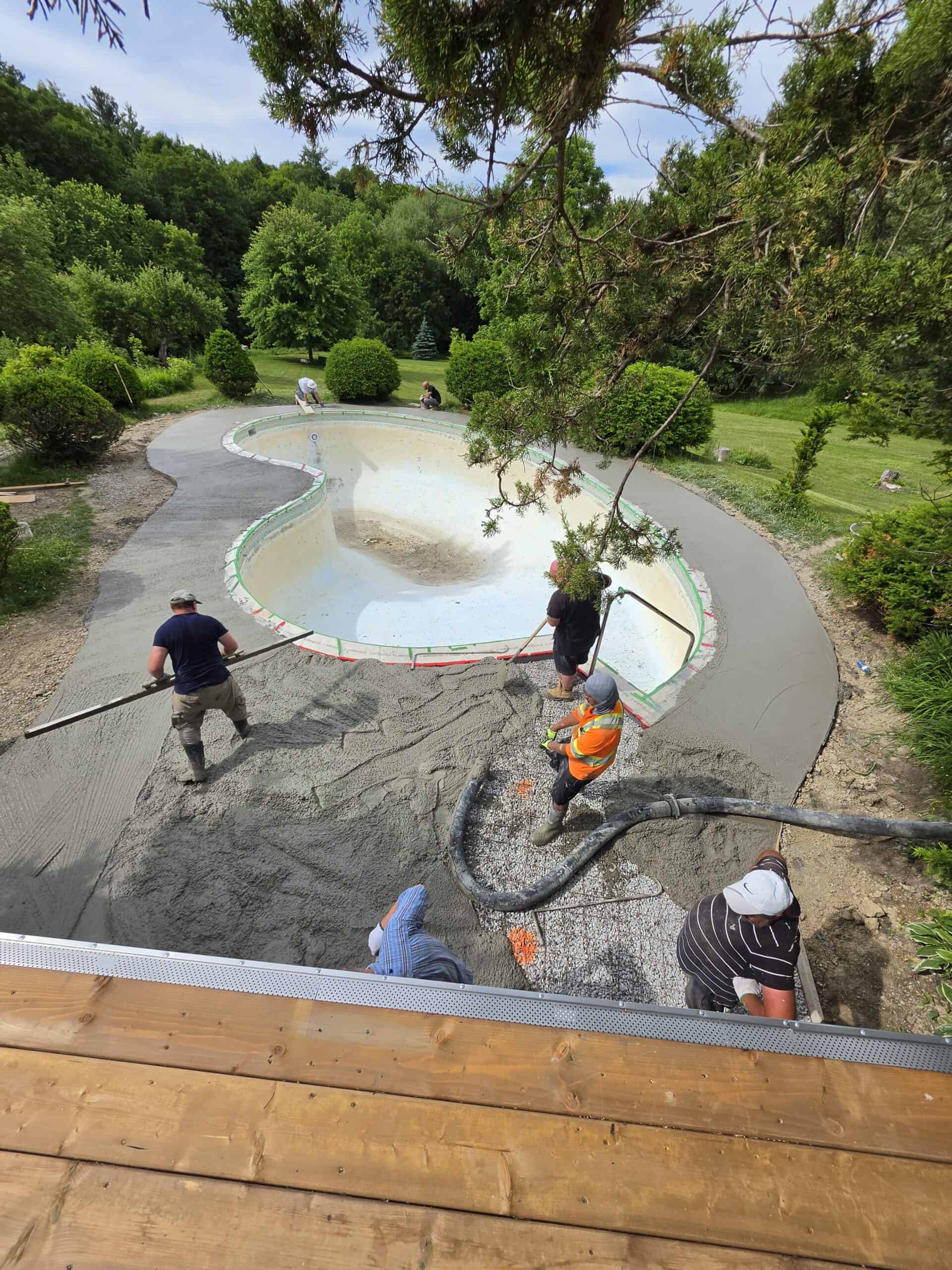 Concrete pumping crew placing concrete around a residential swimming pool.